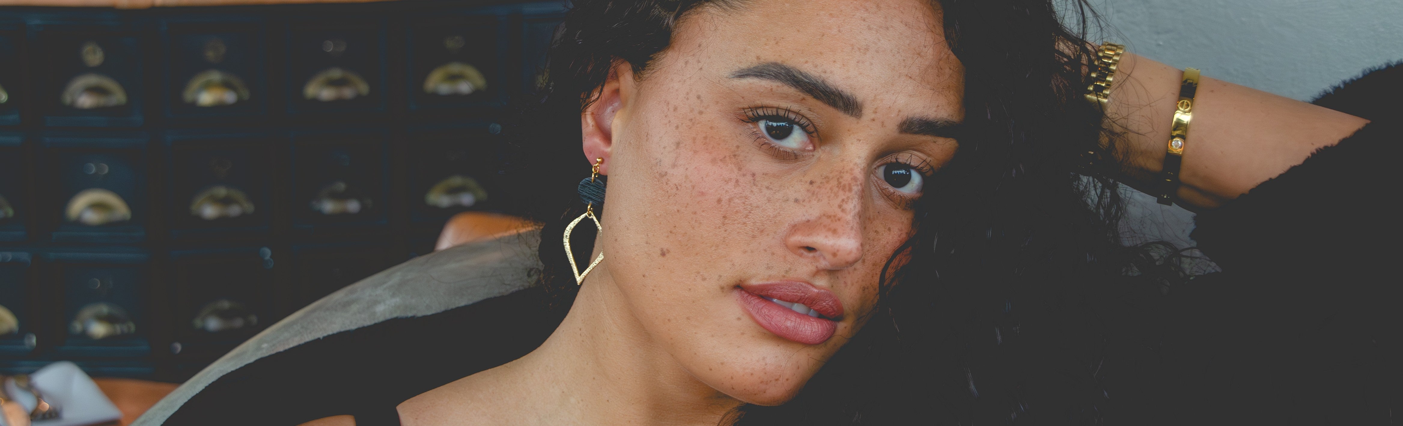 Model With a Black Top wearing Green Hoop Gold Earrings