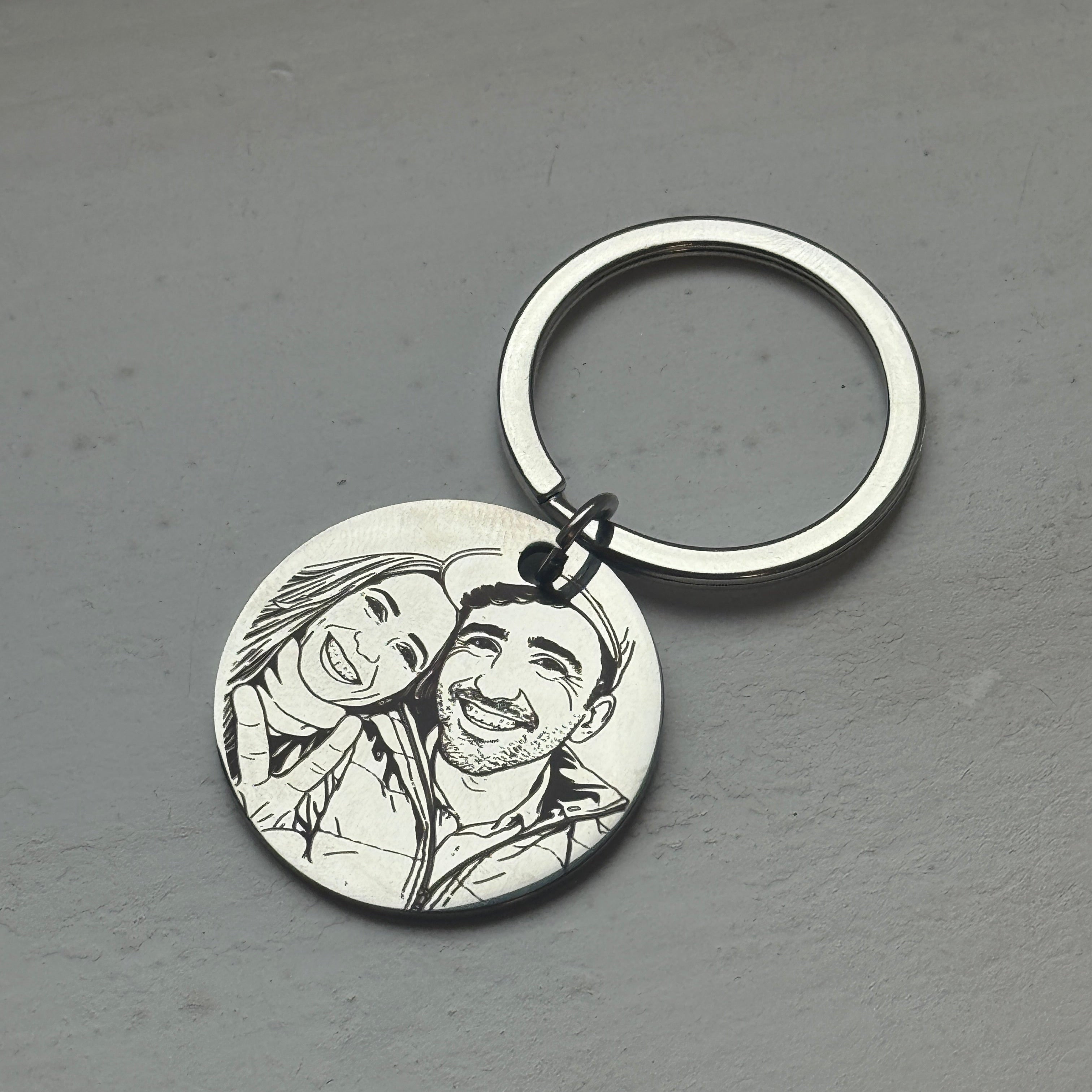 Keychain with engraved image of a couple on a gray surface