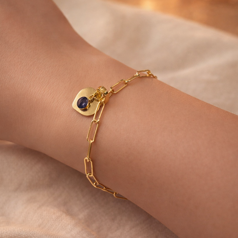 Gold bracelet with a black gemstone on a wrist against a soft background