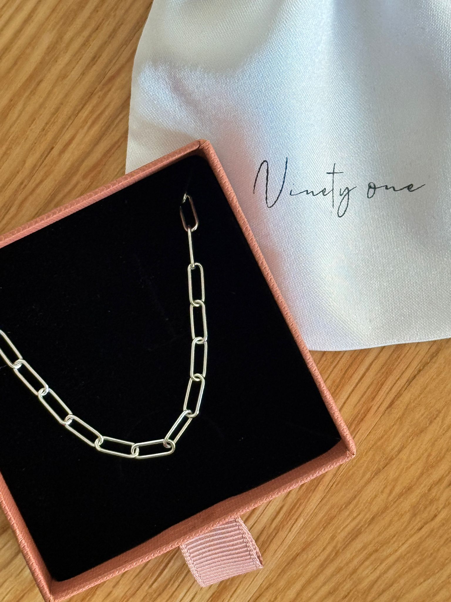 Silver chain necklace in a jewelry box on a wooden surface