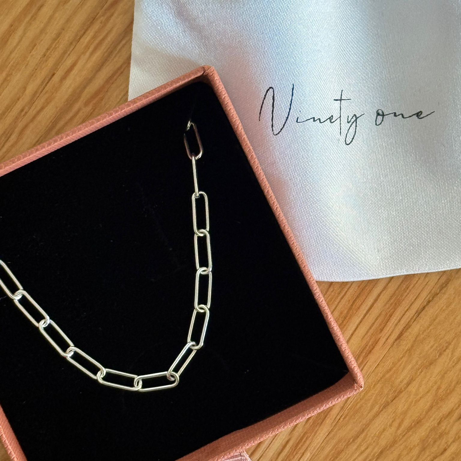 Silver chain necklace in a jewelry box on a wooden surface