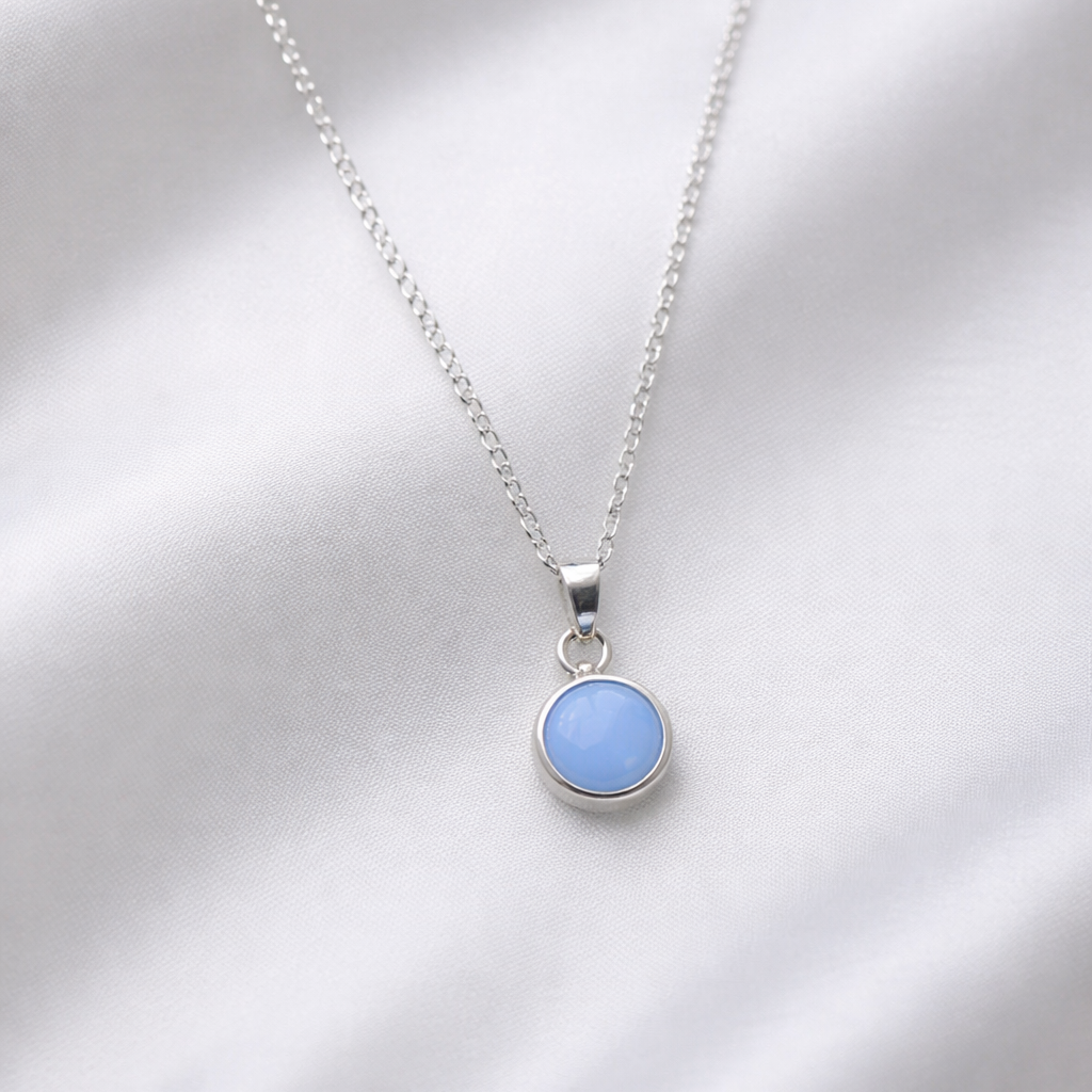 Necklace with a blue pendant on a white satin background
