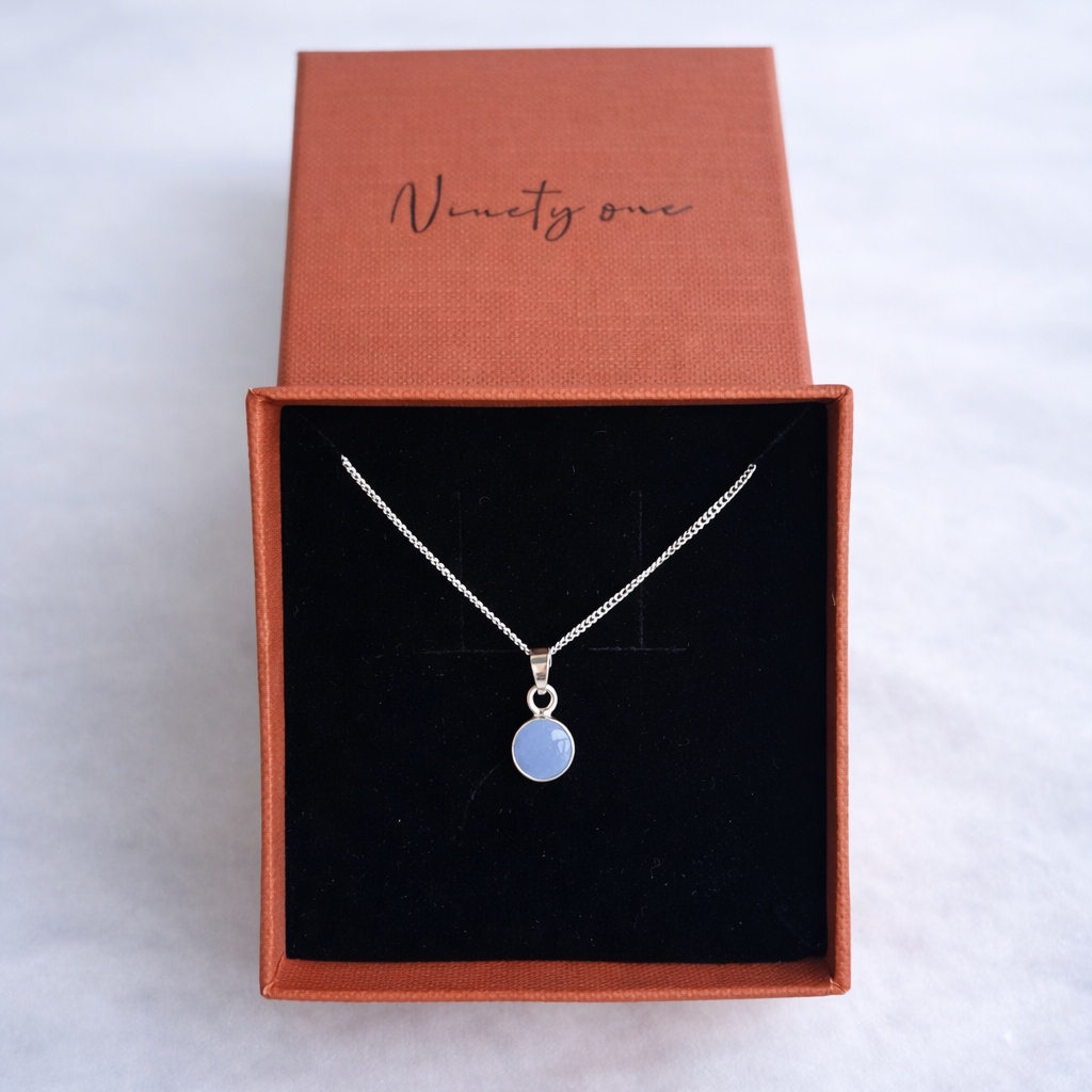 Silver necklace with a blue pendant in a jewelry box on a white background